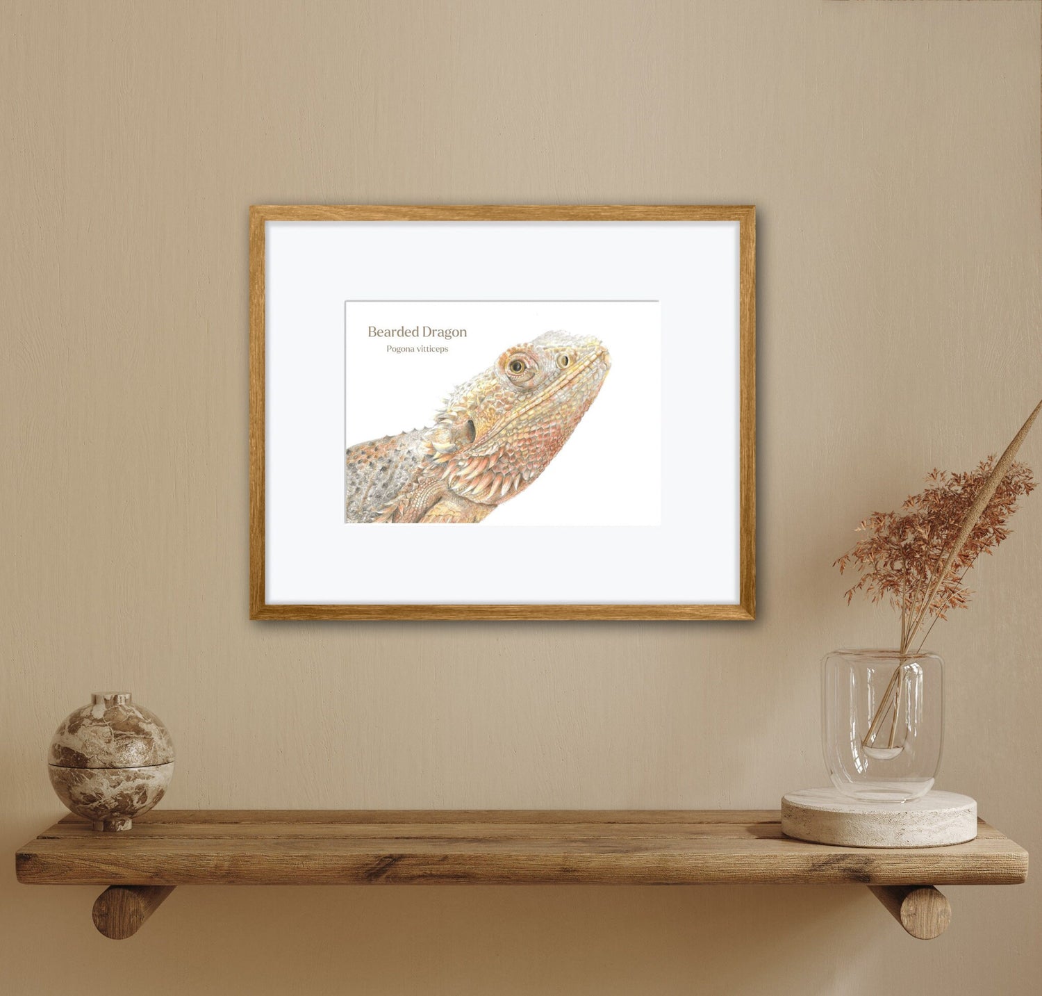 Framed artwork of a bearded dragon on a wall above a wooden shelf with decorative items.