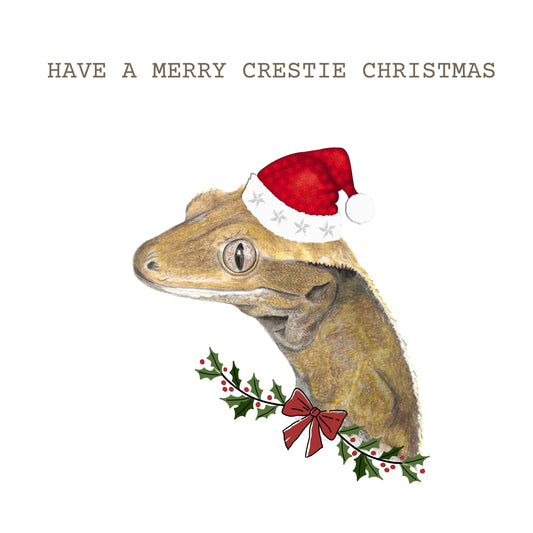 Crested gecko wearing a christmas hat with holly and red bow detail and have a merry crestie christmas text
