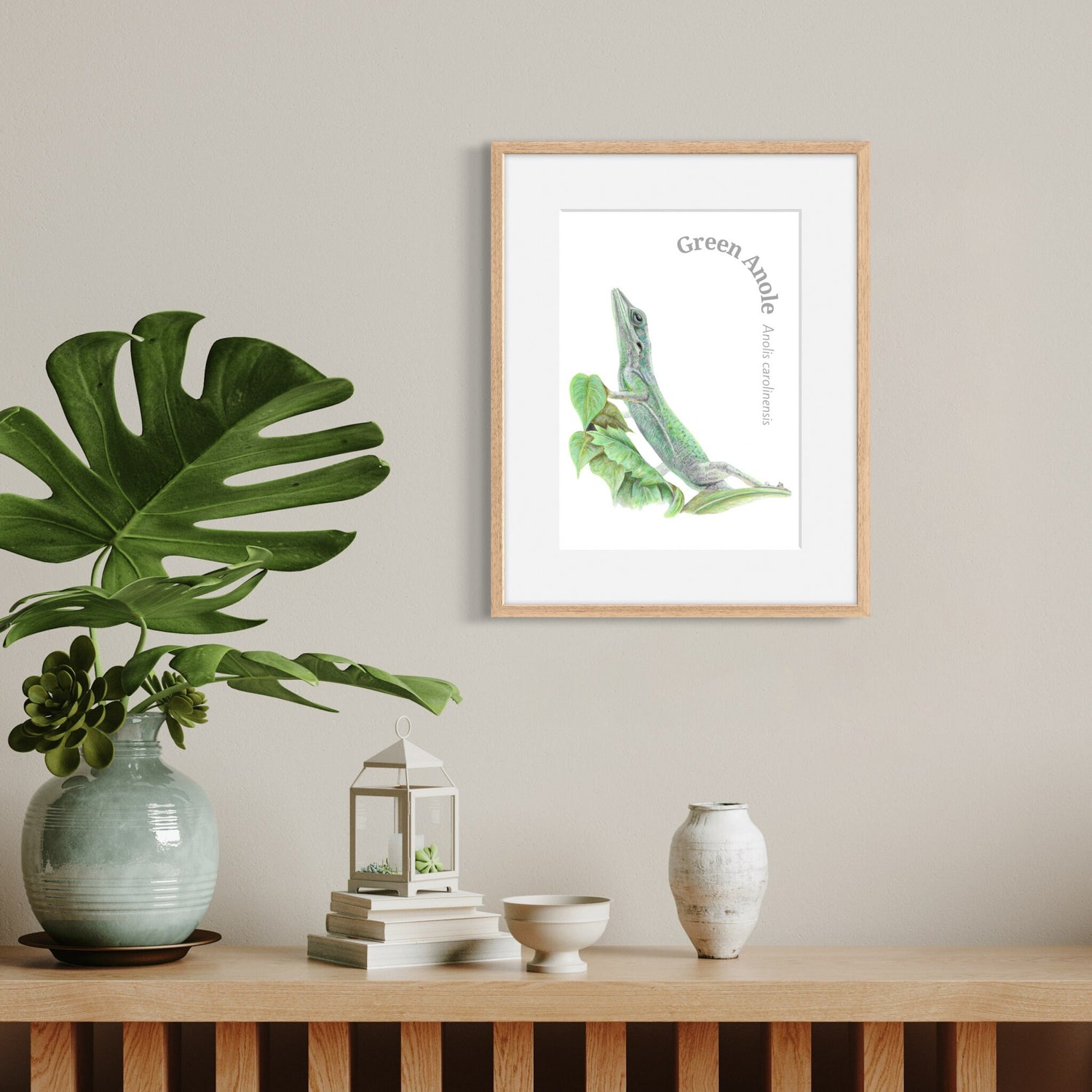 Framed artwork of a green lizard on a wall above a wooden shelf with decorative items.