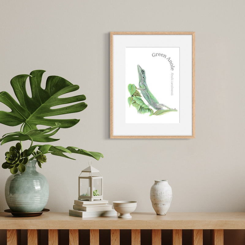 Framed artwork of a green lizard on a wall above a wooden shelf with decorative items.