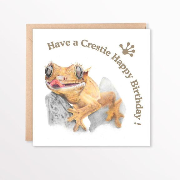 Birthday card with a crested gecko illustration and text on a white background and brown envelope