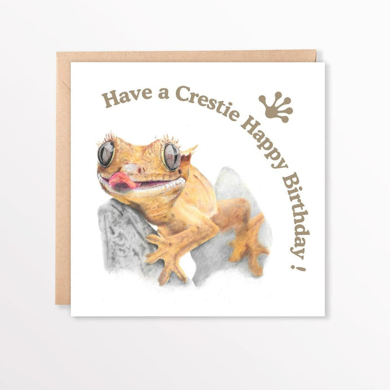 Birthday card with a crested gecko illustration and text on a white background and brown envelope